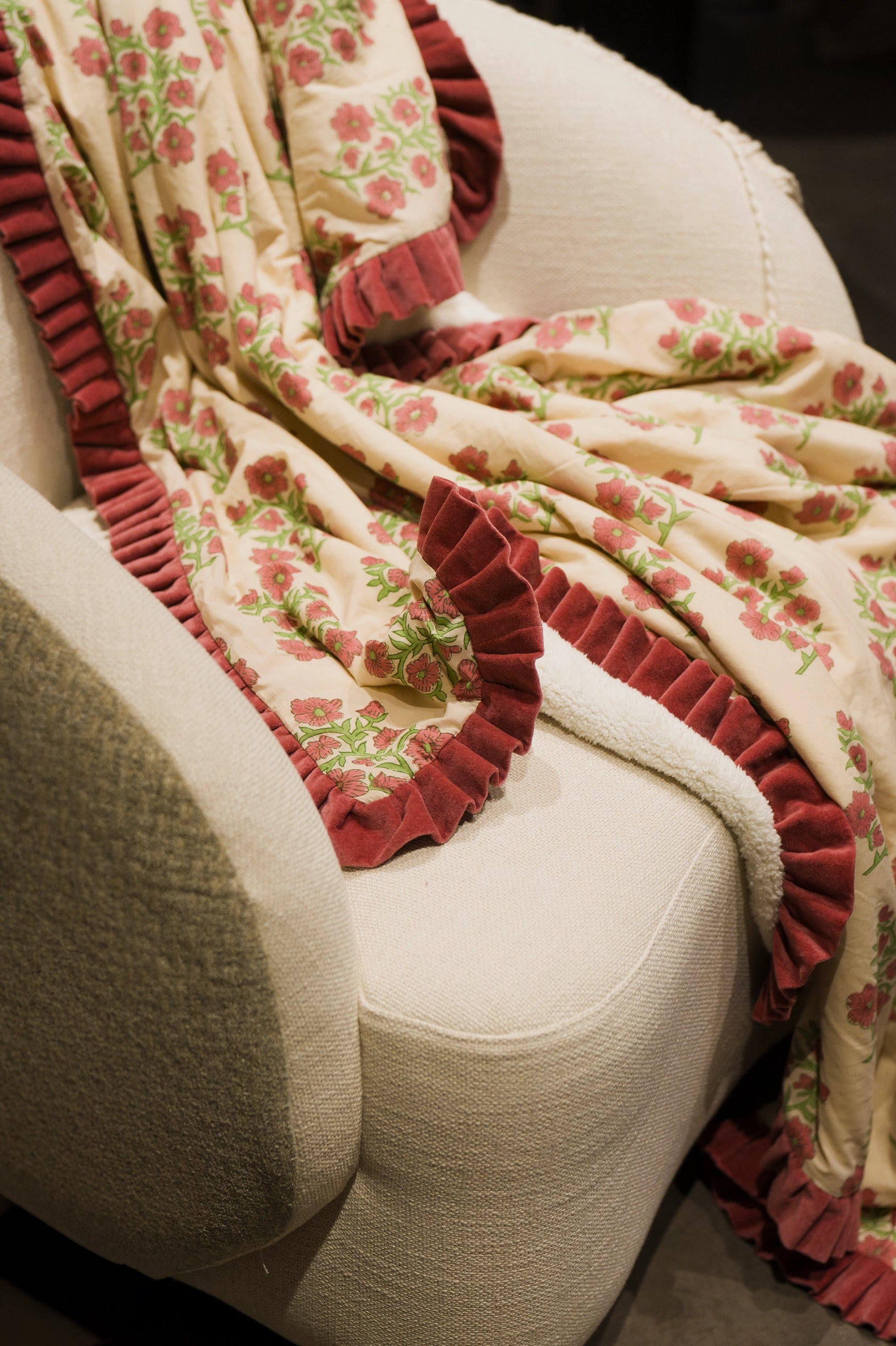 Pink floral hand block print sherpa throw blanket draped over an armchair.