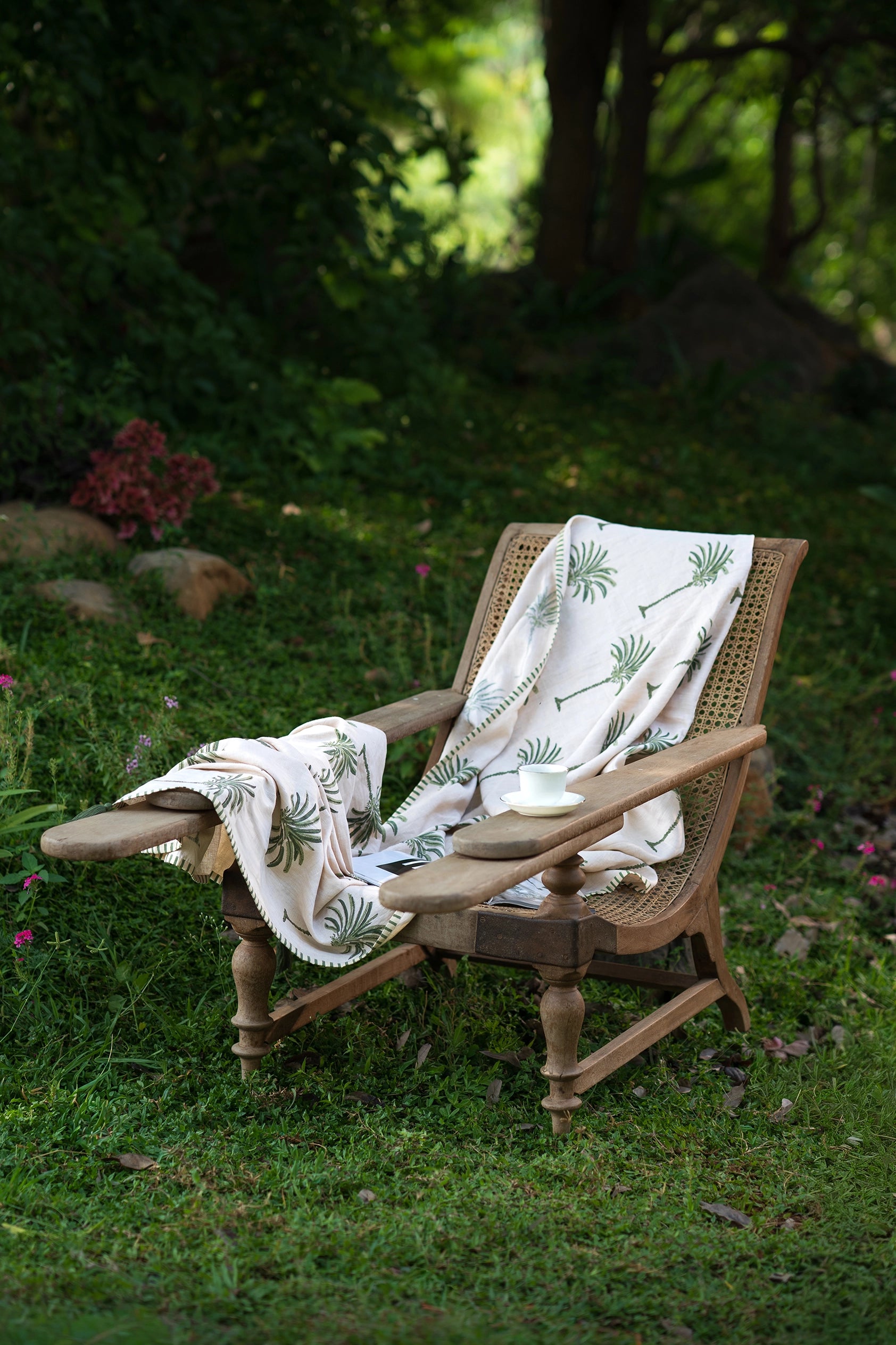 Green hand block print European flax linen throw styled on an outdoor chair and garden setting.