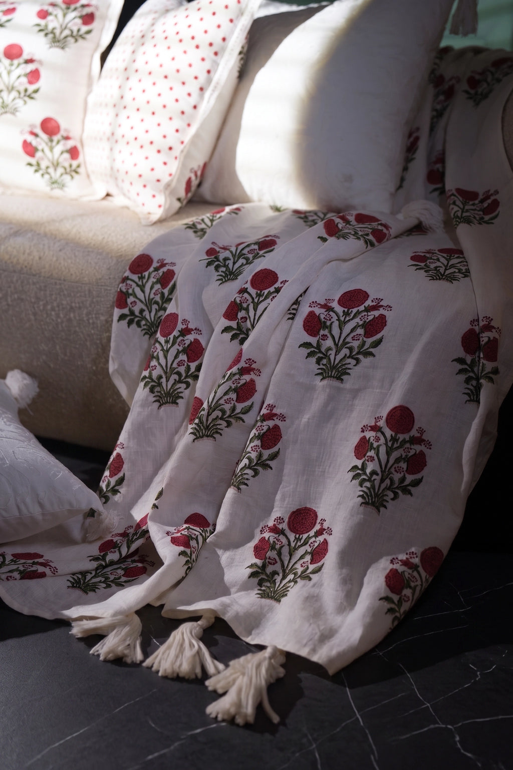 Pink floral hand block print linen throw styled over a sofa with matching floral cushions.