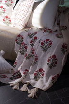 Pink floral hand block print linen throw styled over a sofa with matching floral cushions.
