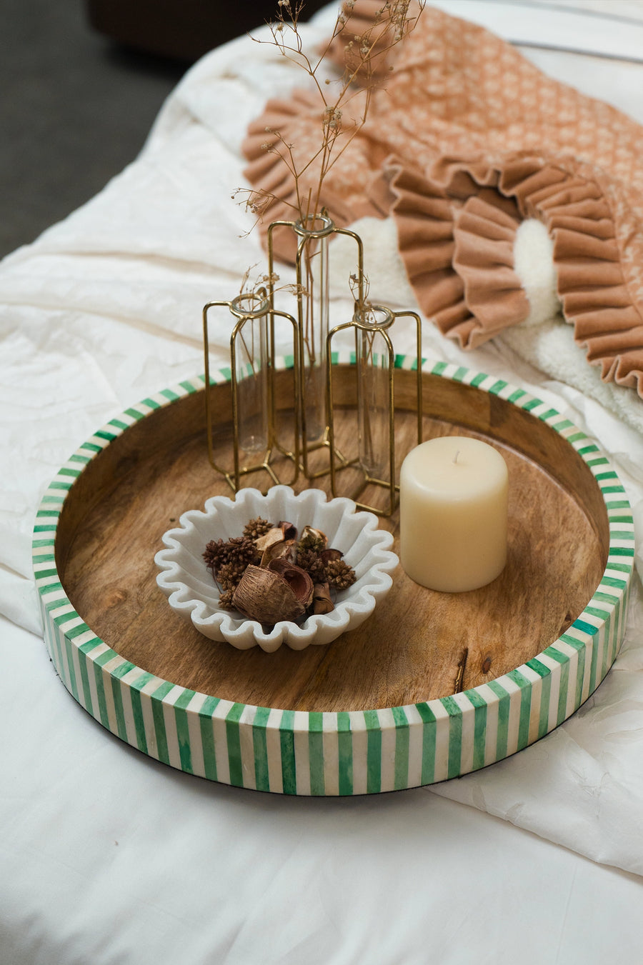 Green and white bone inlay round tray styled on a coffee table with candles and decorative objects.