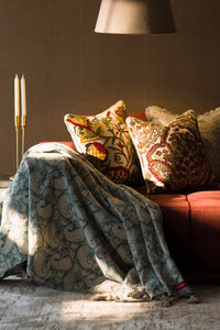Teal hand block print European flax linen throw styled on a sofa in a living room.