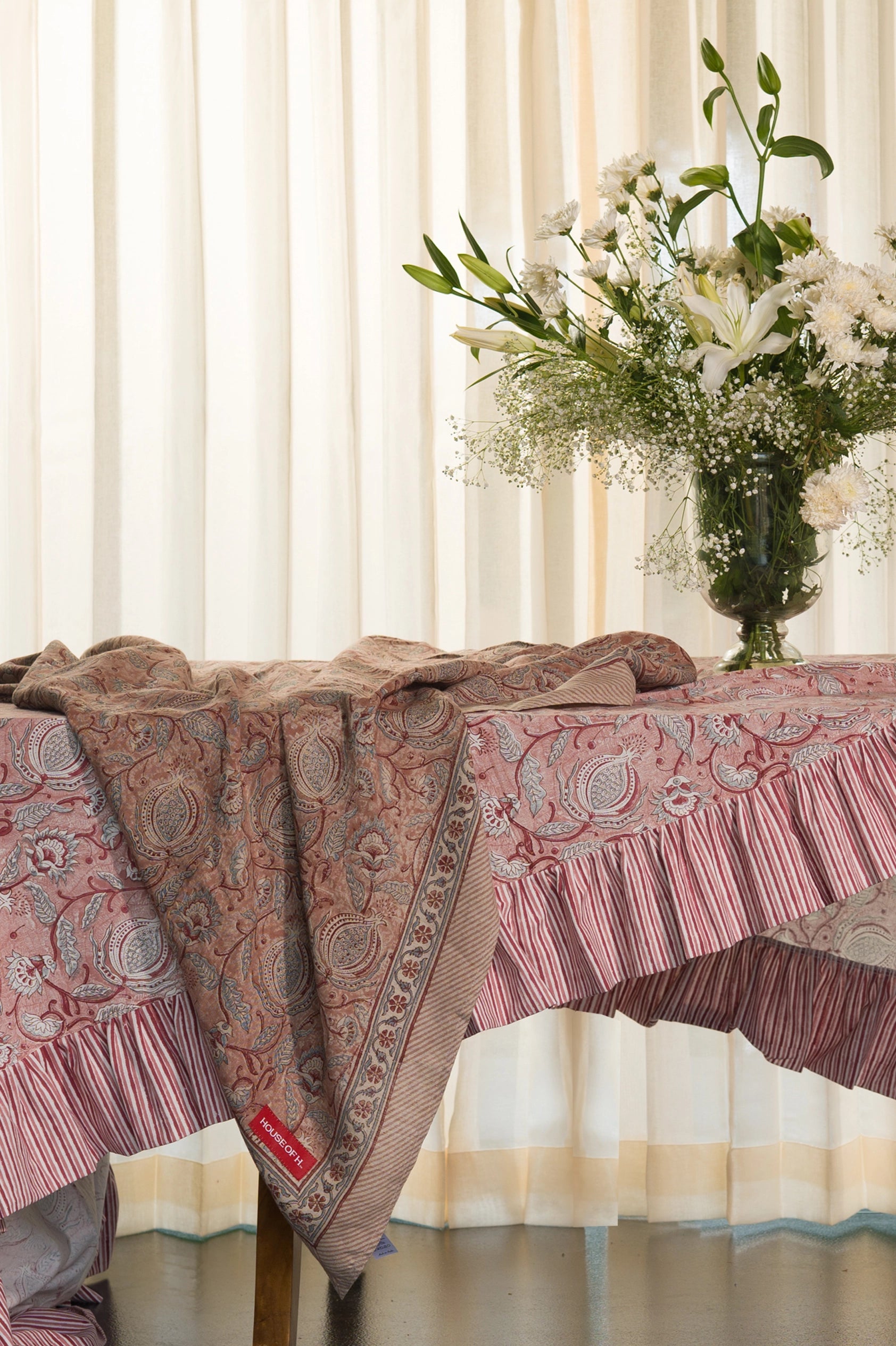 Pink floral hand block print European flax linen tablecloth styled on a dining table with floral arrangement.