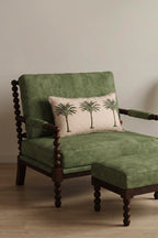 Green upholstered chair with a matching ottoman and decorative European flax linen cushion with palm trees on a neutral background
