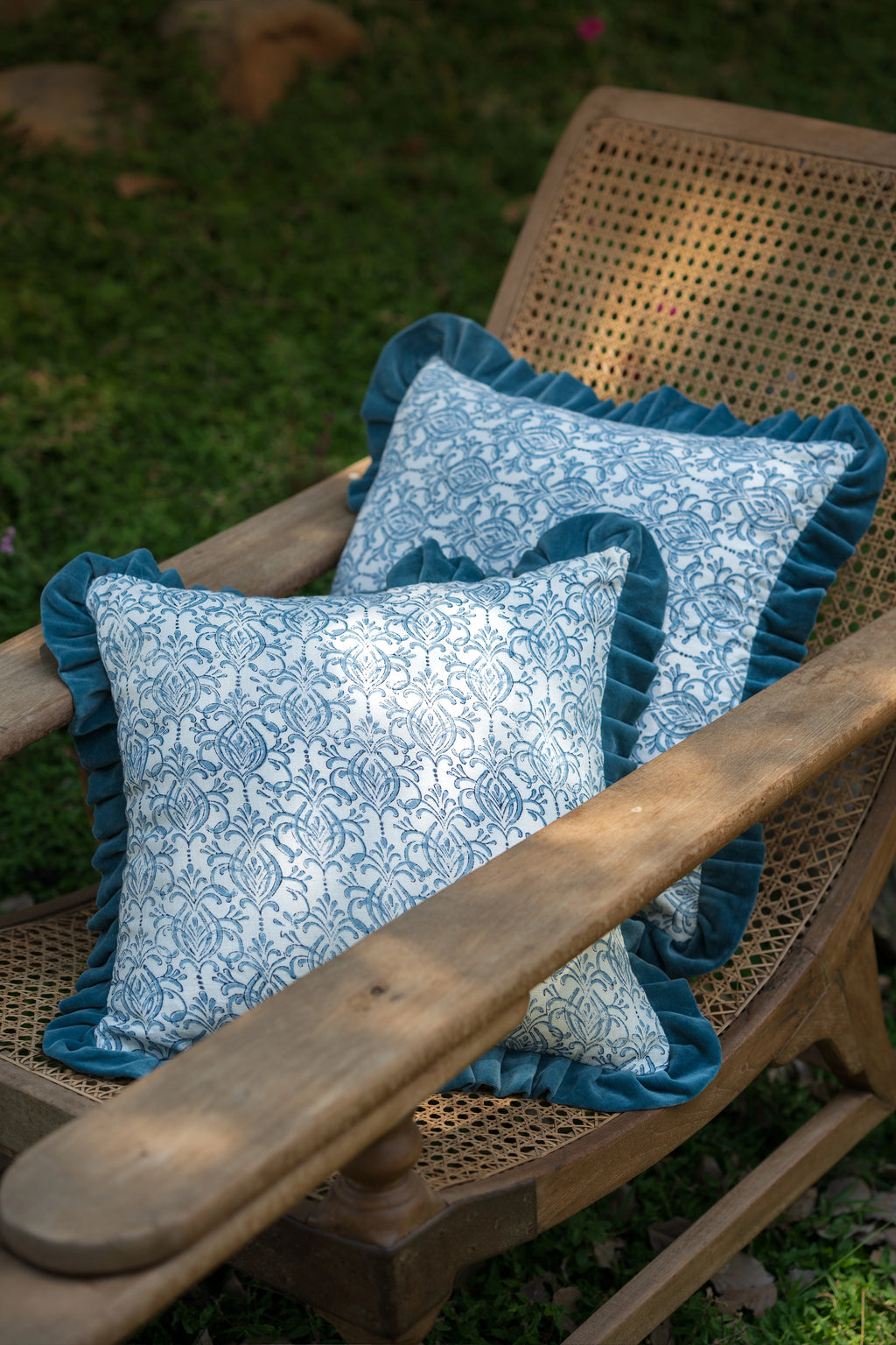 Blue hand block print European flax linen cushion with teal velvet ruffle styled on a timber chair.
