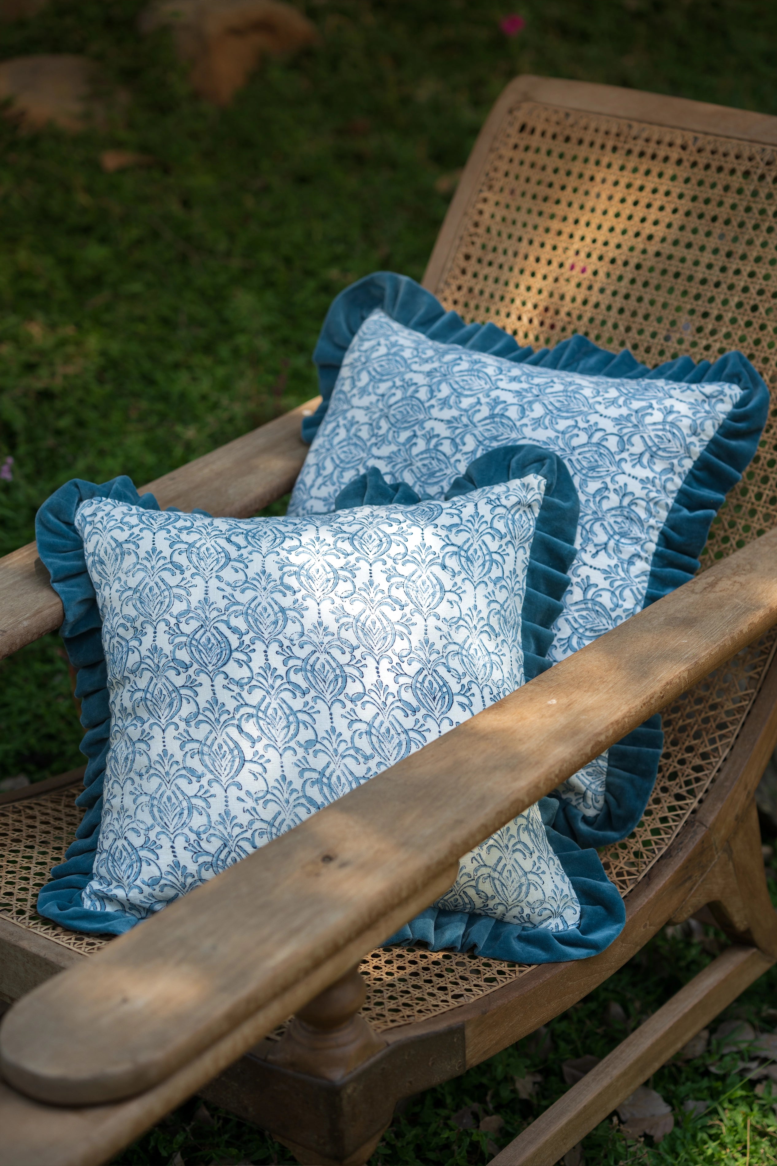 Blue hand block print European flax linen cushion with teal velvet ruffle styled on a timber chair.