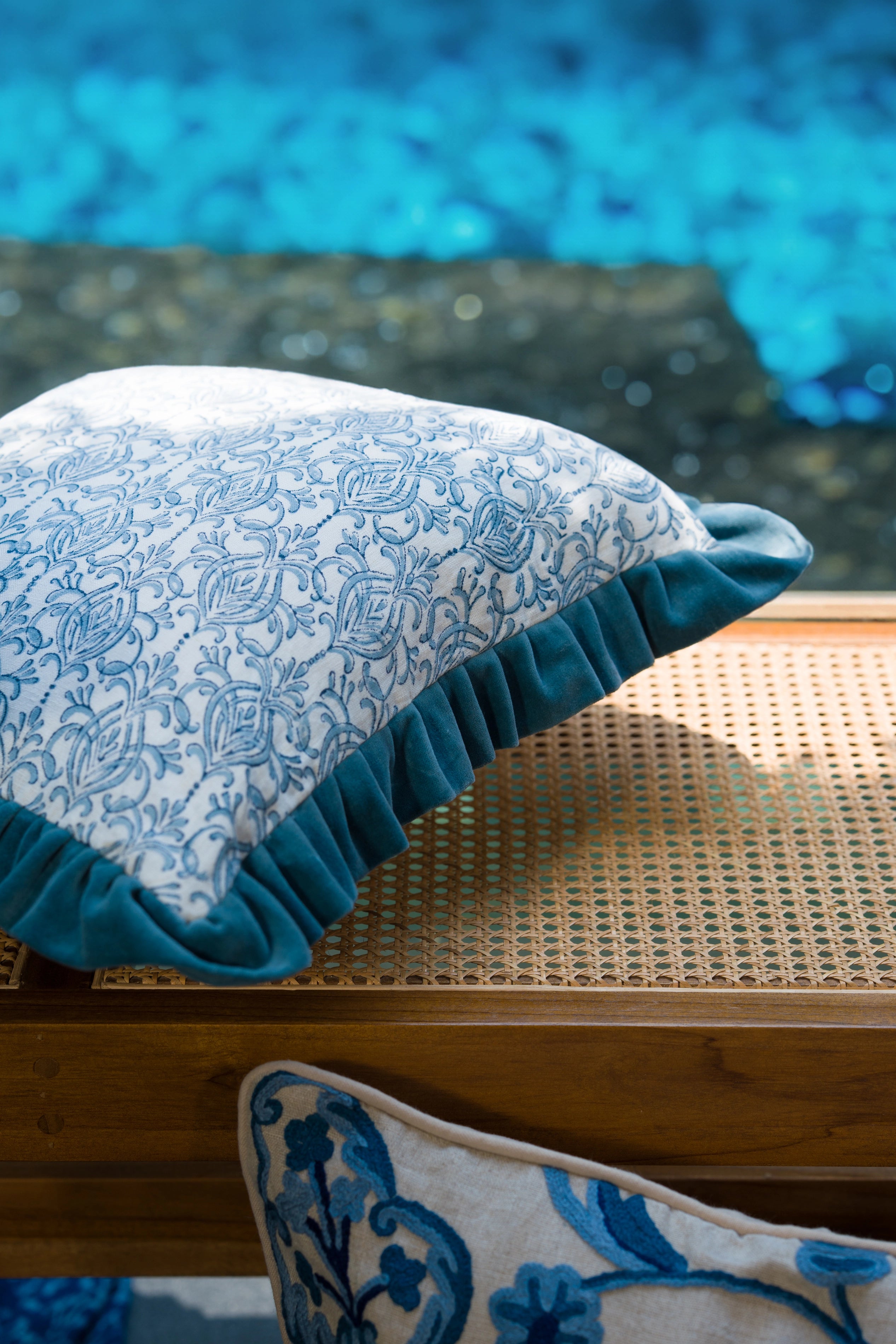Blue hand block print European flax linen cushion with teal velvet ruffle styled on outdoor seating with a matching block print cushion.