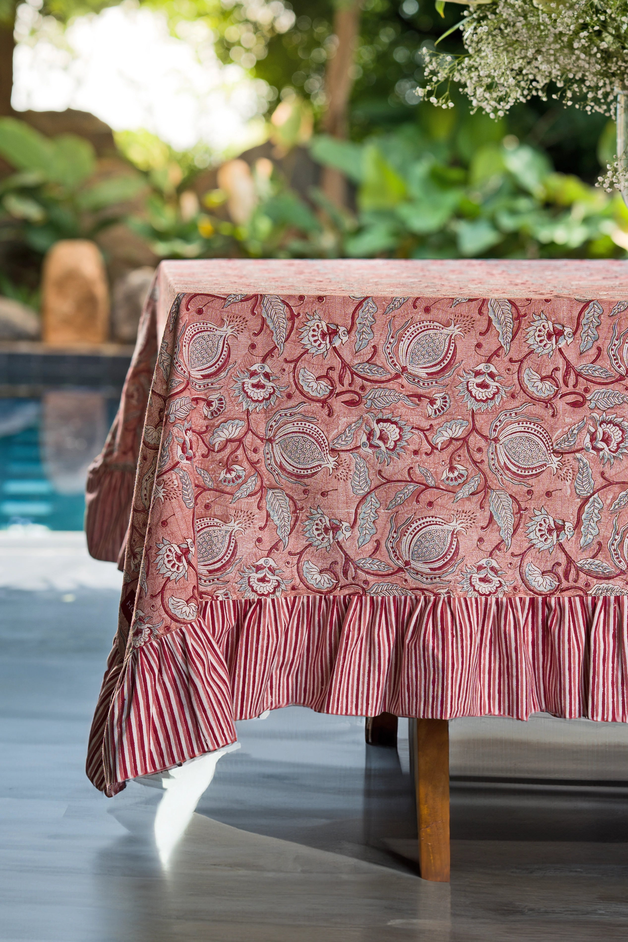 Pink floral hand block print cotton tablecloth styled on an outdoor dining table.