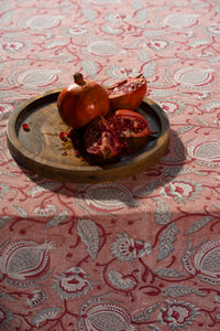 Pink floral hand block print cotton tablecloth styled with tableware on a dining table.