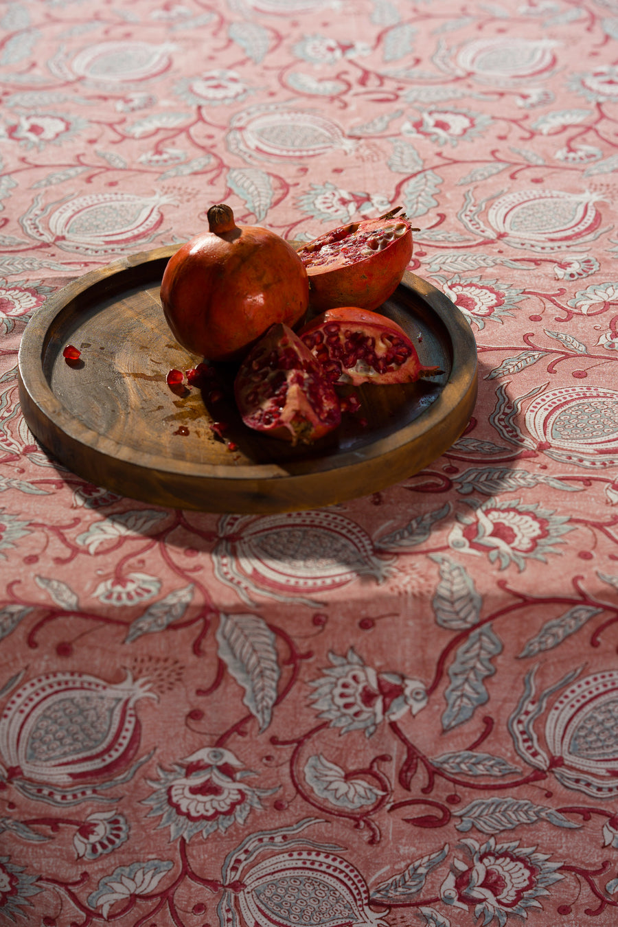 Pink floral hand block print cotton tablecloth styled with tableware on a dining table.