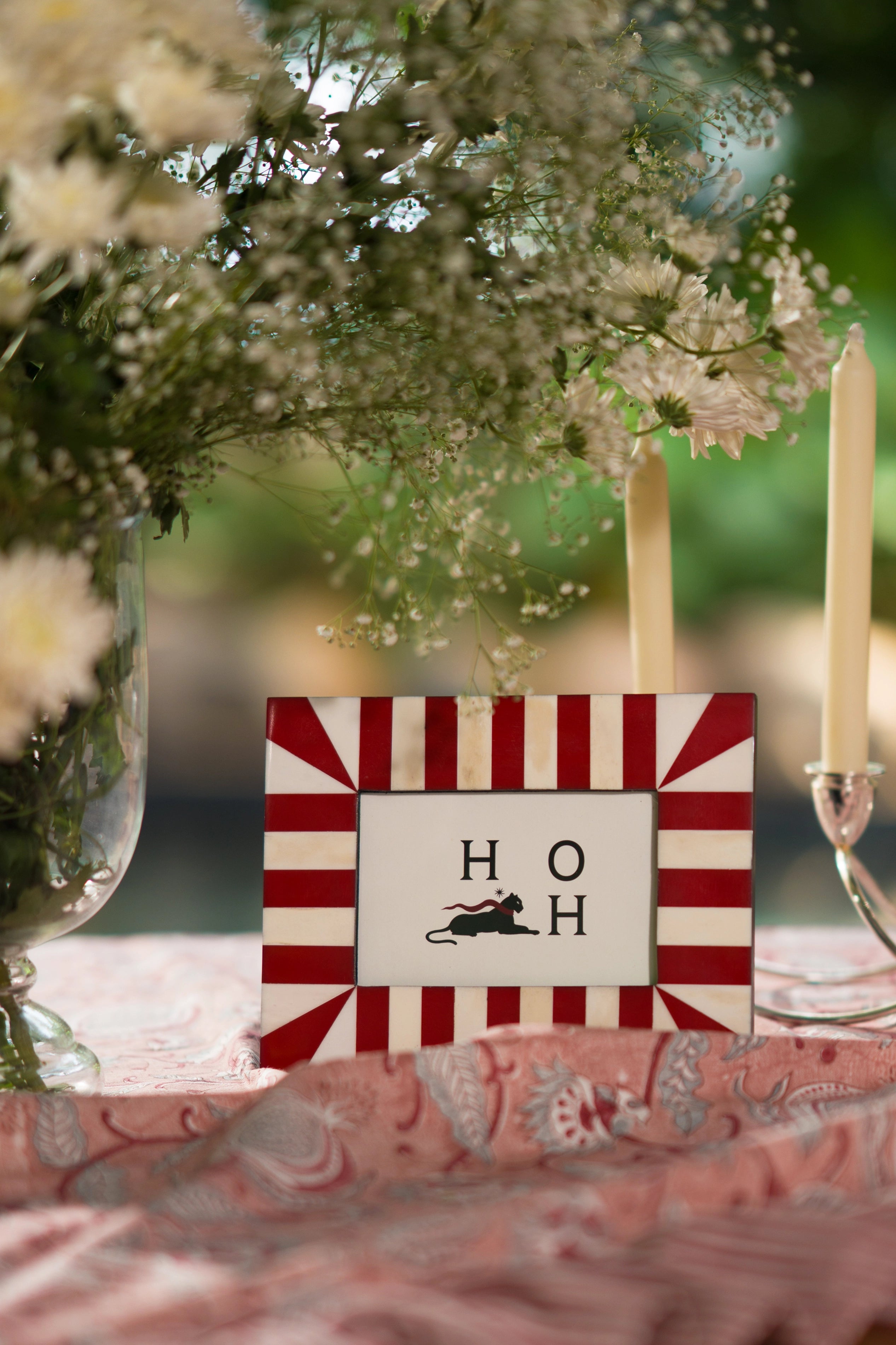 Square red and ivory starburst bone inlay photo frame styled outdoors on a stone surface.
