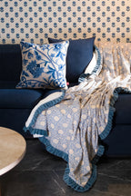 Blue crewel embroidered linen cushion styled with a matching block print throw on outdoor seating.