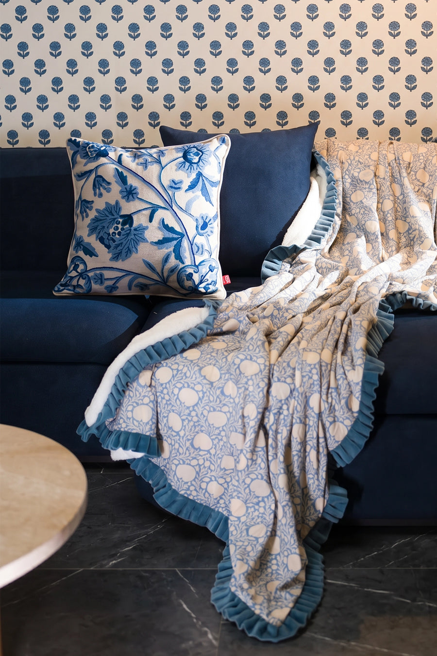 Blue crewel embroidered linen cushion styled with a matching block print throw on outdoor seating.