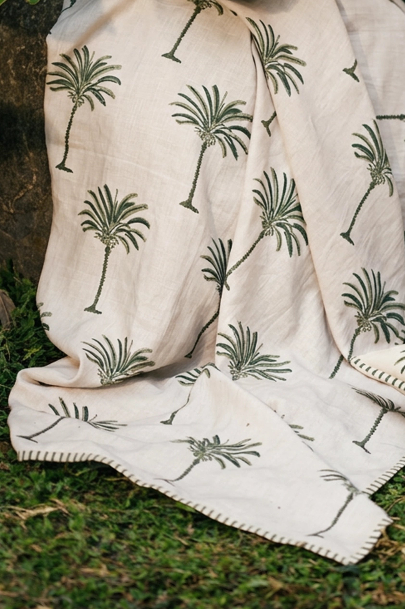 Green hand block print European flax linen throw styled in a garden setting.