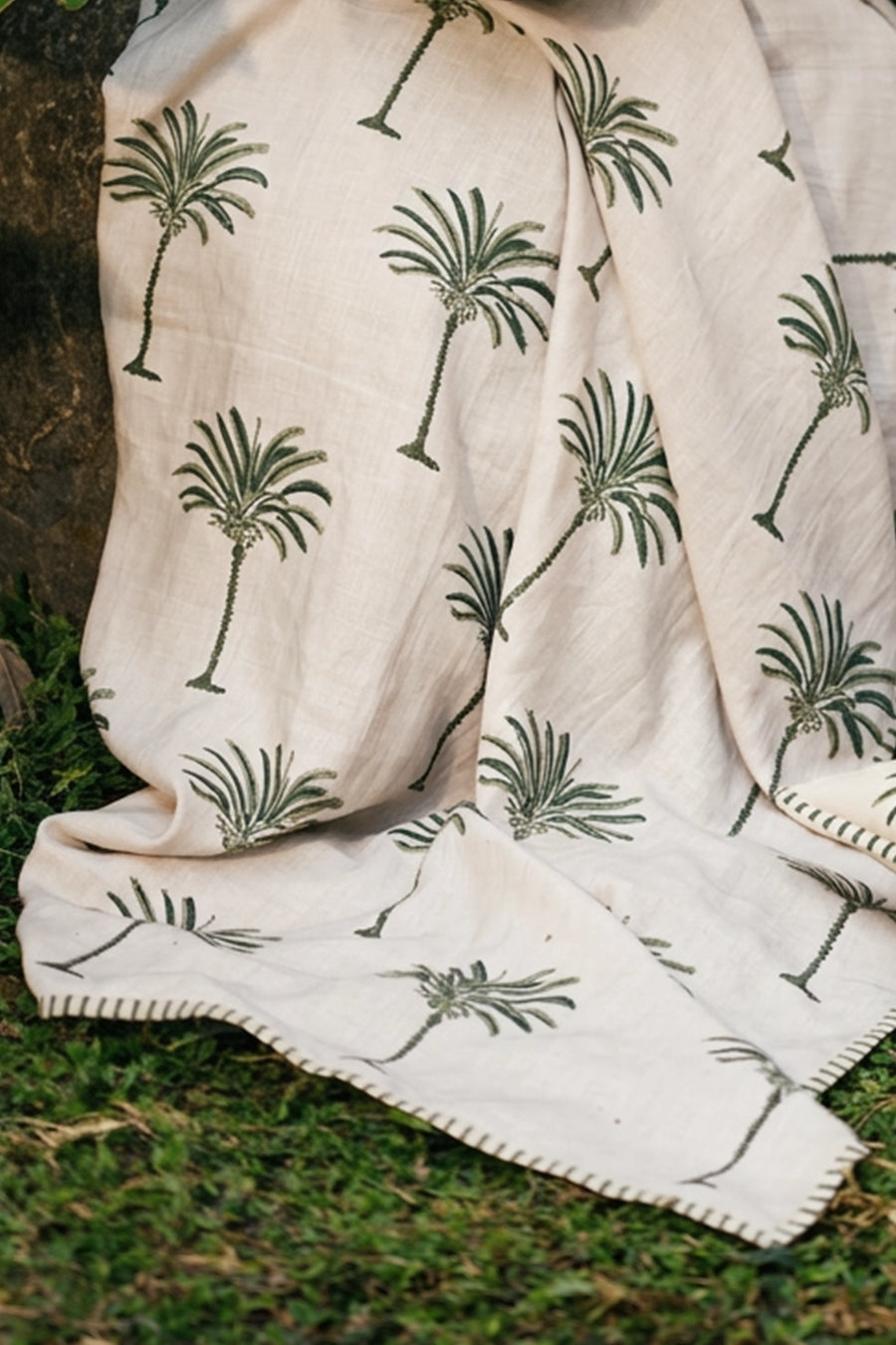 Palm Plume European linen palm throw styled in a garden setting.