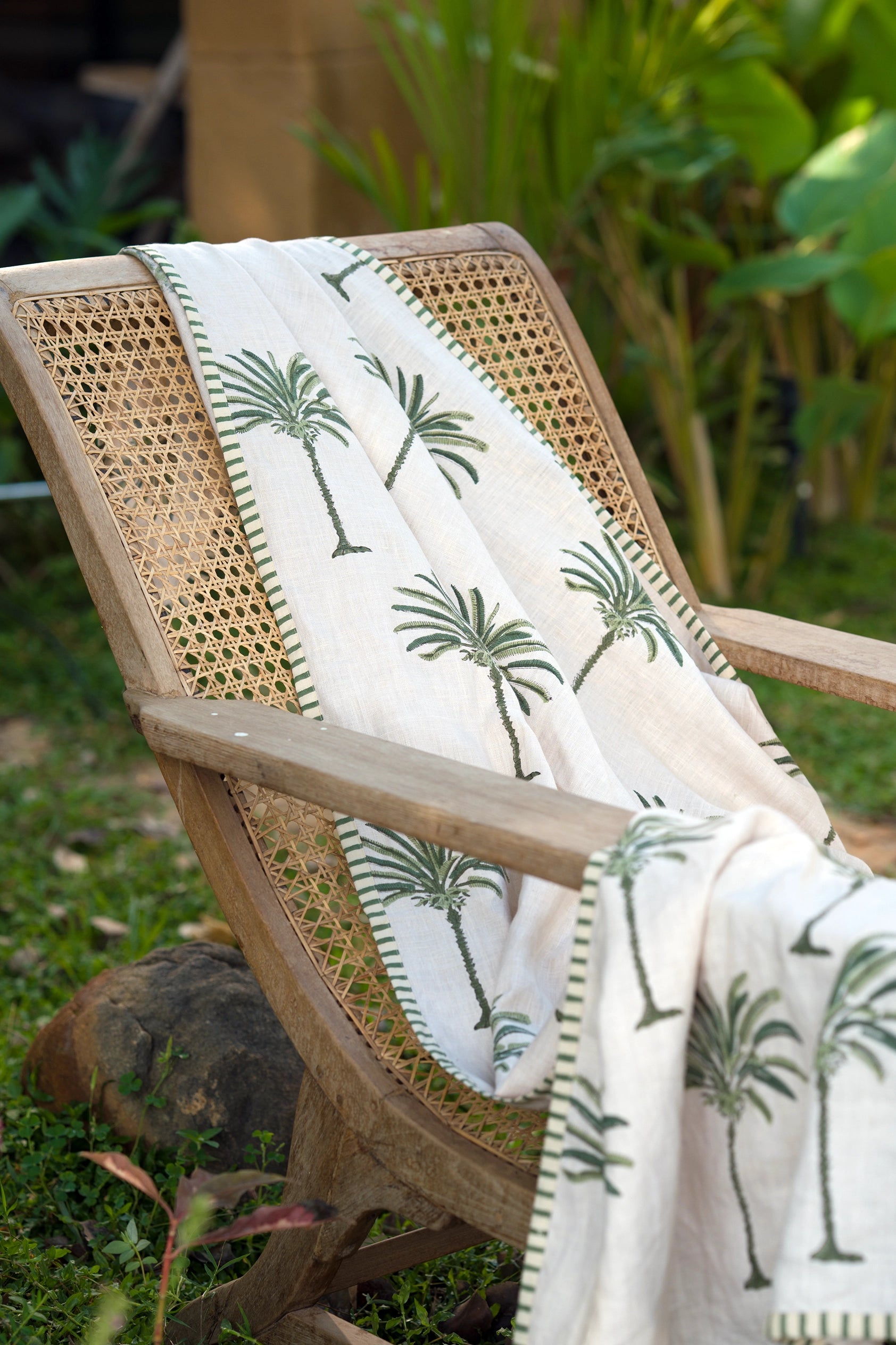 Green hand block print European flax linen throw styled on an outdoor chair.