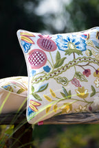 Primavera embroidered floral European linen cushion styled among garden foliage.