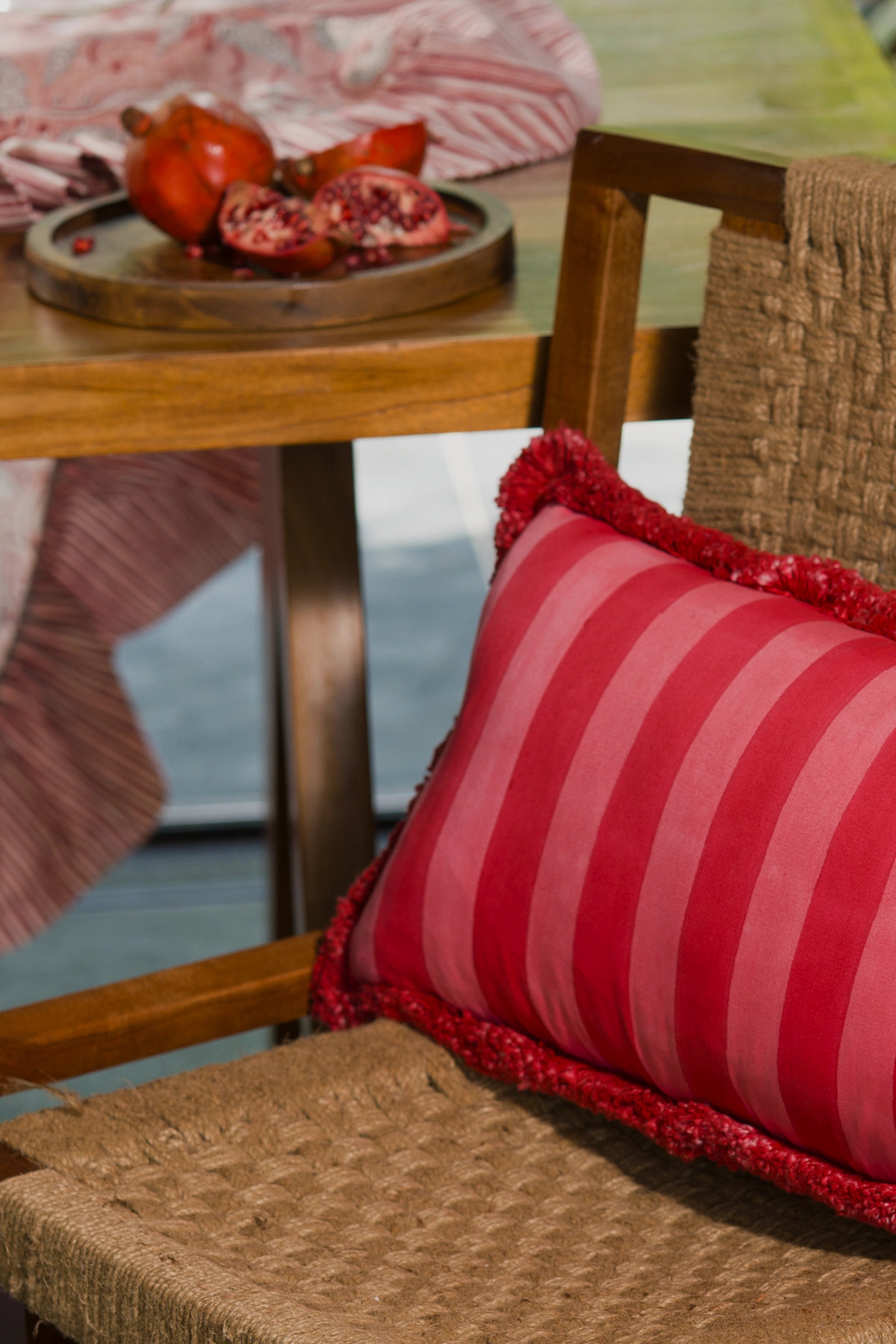 Red striped 1000 thread count cotton lumbar cushion styled on outdoor seating.