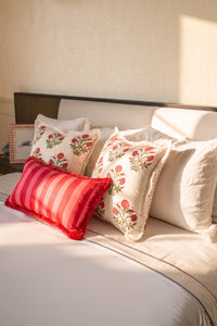 Red striped 1000 thread count cotton lumbar cushion styled on a bed with coordinating cushions.