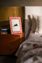 Rectangular red and ivory harlequin bone inlay photo frame styled on a bedside table.