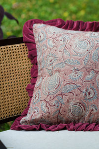 Square pink floral hand block print linen cushion with ruffled edge styled on outdoor seating.
