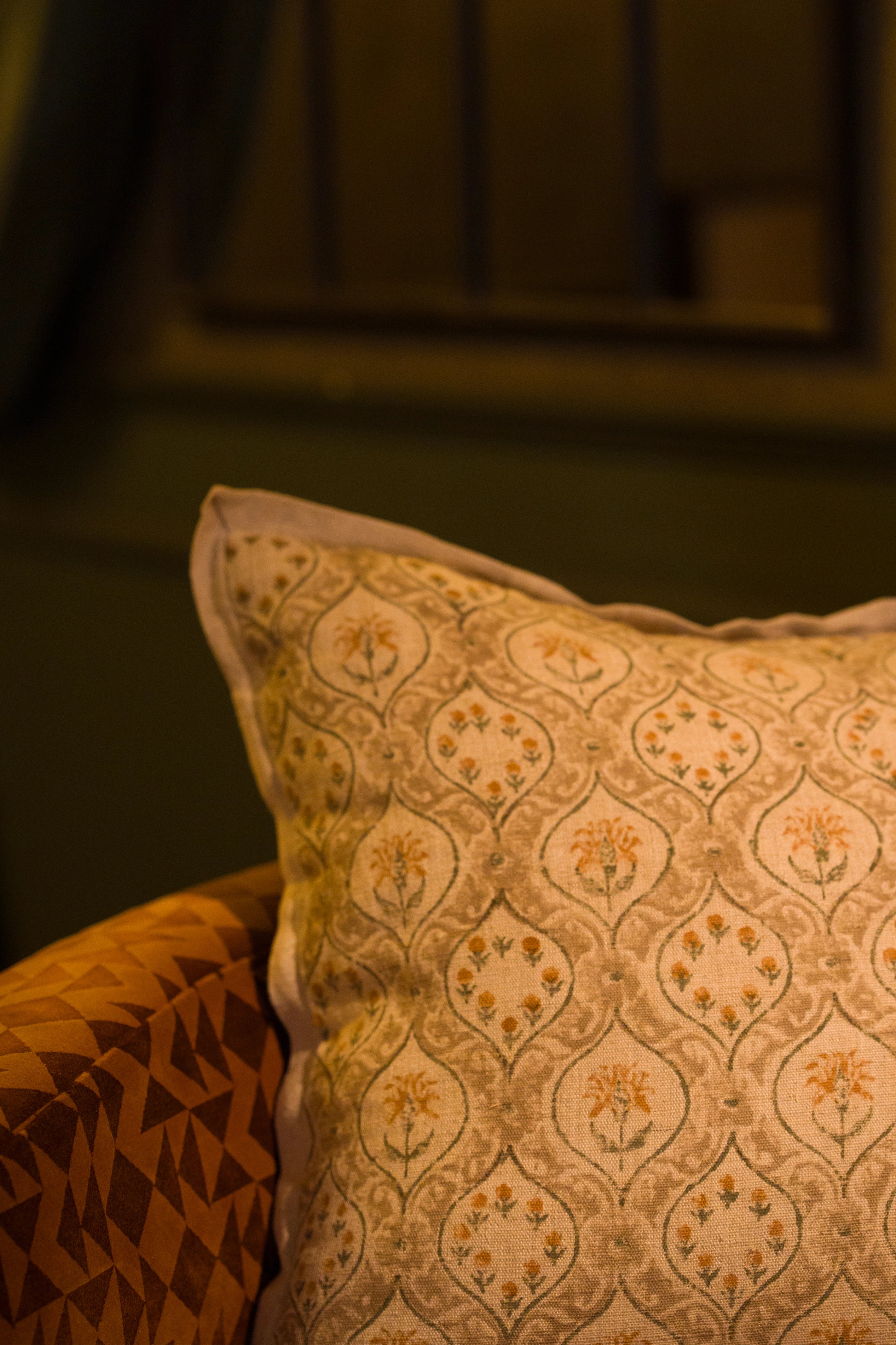 Taupe hand block print European flax linen cushion styled on a woven chair.