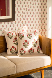 Square pink floral hand block print linen cushion styled on a sofa with coordinating cushions.