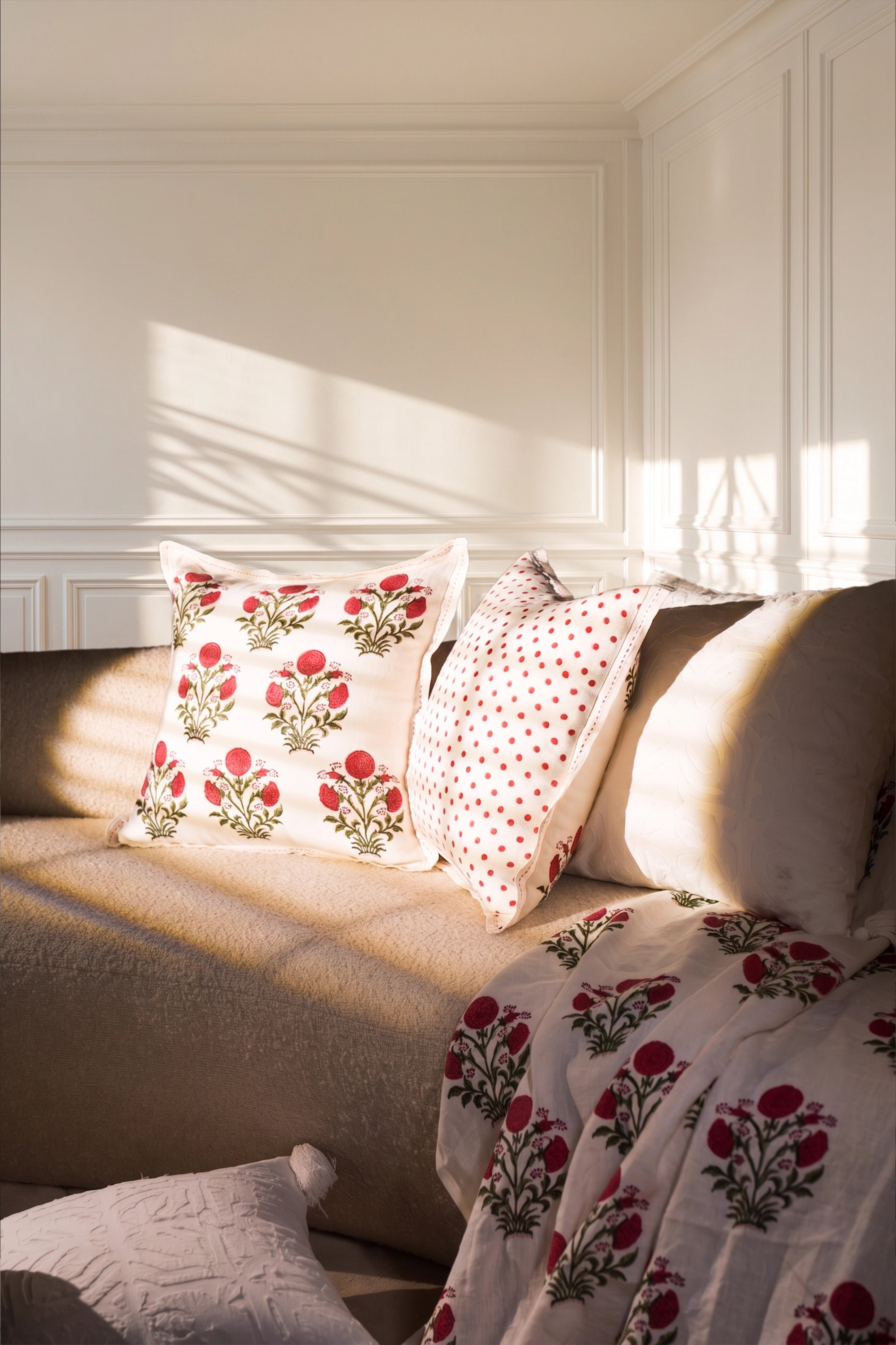 Square pink floral hand block print linen cushion styled on a sofa in a sunlit living room.