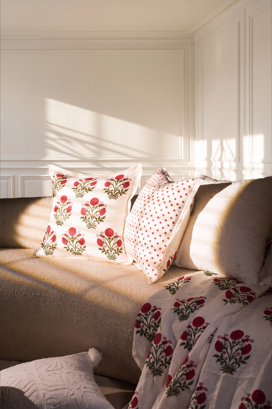 Square pink floral hand block print linen cushion styled on a sofa in a sunlit living room.