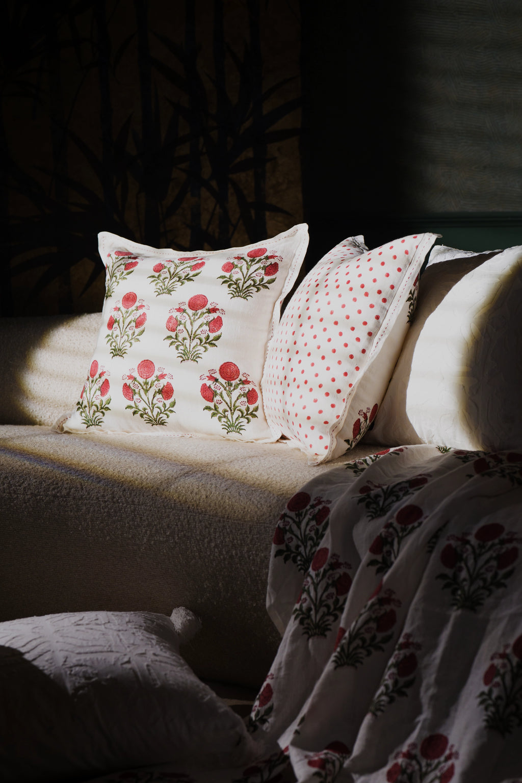 Square pink floral hand block print linen cushion styled on a sofa in a living room.
