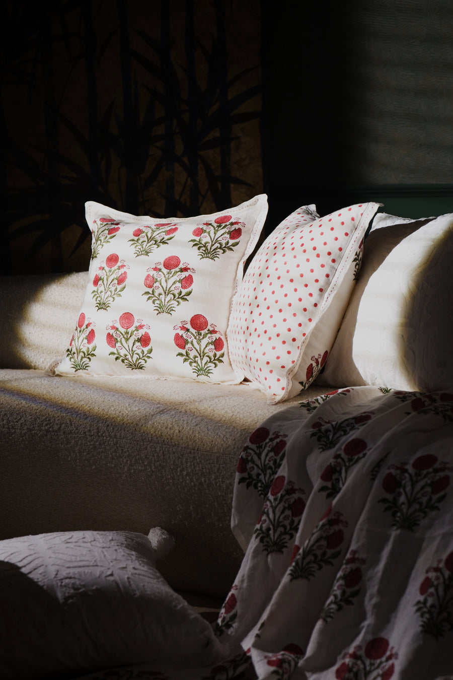 Square pink floral hand block print linen cushion styled on a sofa in a living room.